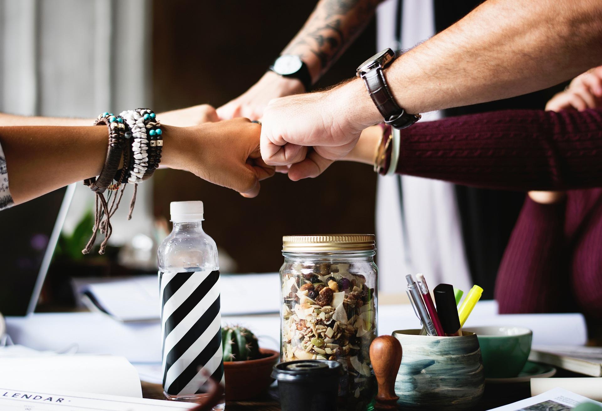 Des membres d’une équipe se saluent en se tapant le poing autour d’une table de travail.